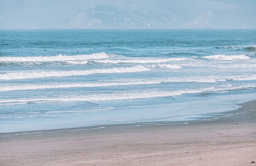 Wave splashes close-up. Crystal clear sea water hitting rock formations in the ocean in San Francisco Bay, blue water, pastel colors.
