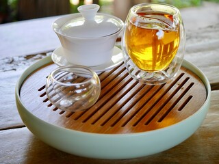 tea from glass teapot on wooden serving tray, Tea making process, Glass teapot at the tea ceremony close up, A cup of balance filled with tea, Healthy fermented puerh herbal teachinese ceremony
