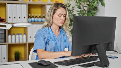 Young blonde woman doctor using computer working at clinic