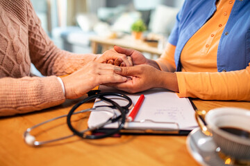 Close up cropped shot patient holding hands with caregiver at home