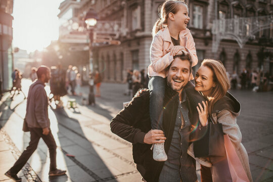 Smiling young parents with little daughter downtown in city