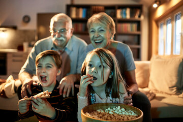 Little children watching movie with grandparents at home