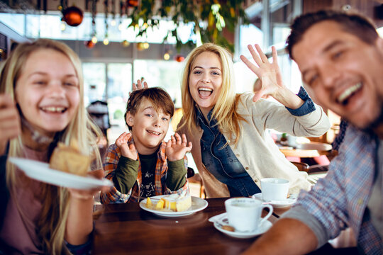 Happy young family sitting in cafe looking at camera selfie concept