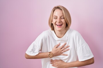 Young caucasian woman standing over pink background smiling and laughing hard out loud because...