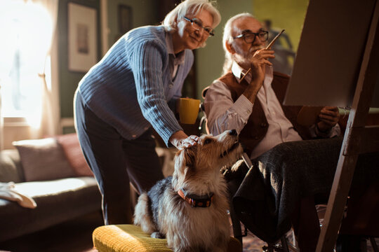 Senior man painting with his wife and dog at home