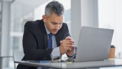 Young hispanic man business worker using laptop stressed at office