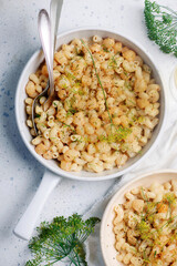 Scallop with creamy pasta in a white frying pan.top view
