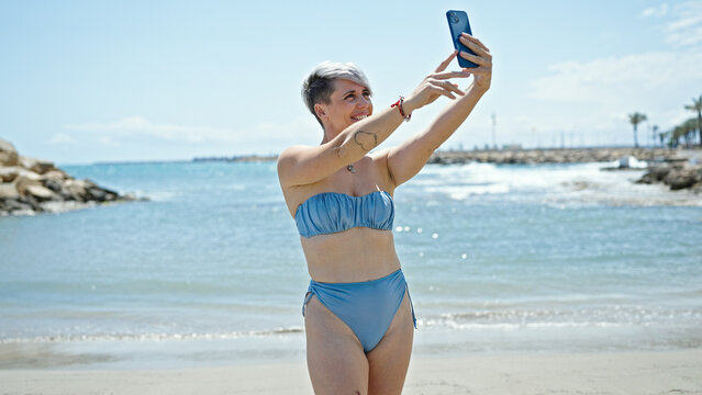 Young woman tourist wearing bikini make selfie by smartphone at beach