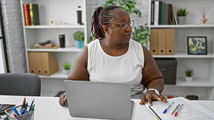 Focused african american woman worker excelling in business. working diligently at her laptop, this...