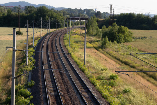 View from above of a double-track electrified railway line leading through the rural countryside.