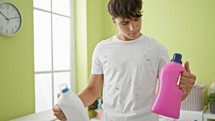 Young hispanic teenager tackles household chores, choosing detergent for his dirty t-shirt in the laundry room