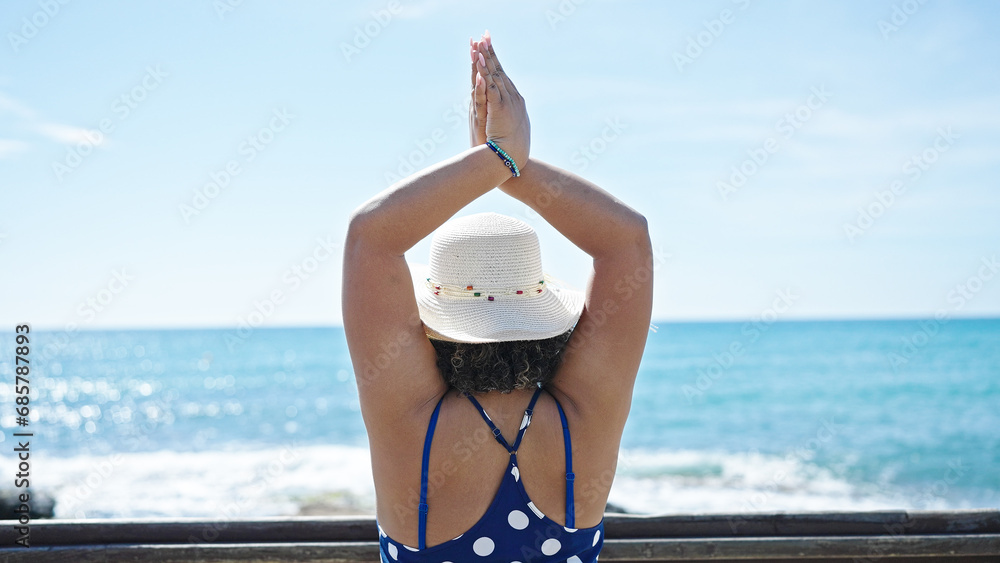 Canvas Prints Young beautiful latin woman tourist wearing summer hat doing yoga exercise at seaside