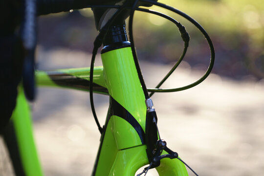 bike frame close up (bicycle head tube with gear and brake cables, shifter, headset spacers) yellow green isolated macro shot with sun glow