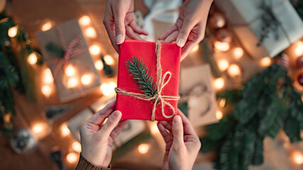 Top view - hands of woman getting surprise handmade red Christmas gift from her girlfriend on...