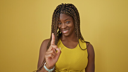 African american woman smiling confident with finger up over isolated yellow background