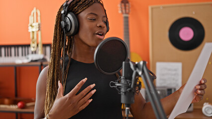 Fototapeta na wymiar African american woman musician smiling confident singing song at music studio