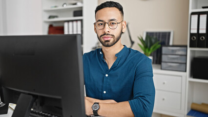 Fototapeta na wymiar Young hispanic man business worker using computer with serious face at the office