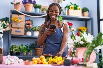 African american woman florist make photo by smartphone to bouquet of flowers and envelope letter at flower shop