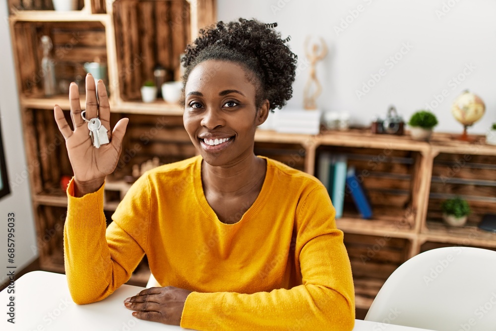 Wall mural african american woman smiling confident holding key of new house at home