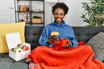 African american woman having breakfast sitting on sofa at home