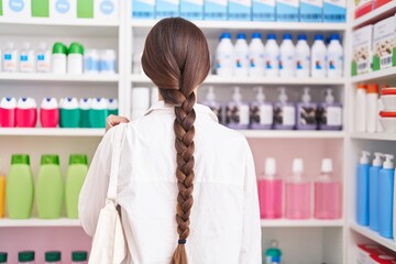 Young beautiful hispanic woman customer looking shelving at pharmacy