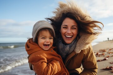 Happy Latin mother and daughter having fun on the beach during