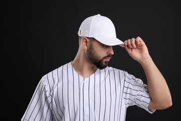 Man in stylish white baseball cap on black background