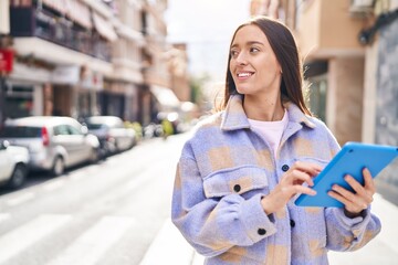 Young beautiful hispanic woman smiling confident using touchpad at street