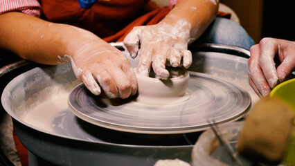 A female expert potter teaches viewers the art of pottery. Close-up of her hands working with clay. The concept of manual labour, art and craftsmanship.