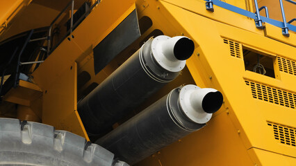 Close-up of two exhaust pipes of a dump truck. Exhaust system of the world's largest dump truck. Yellow huge lorry.