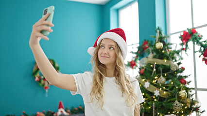 Young blonde woman make selfie by smartphone celebrating christmas at home
