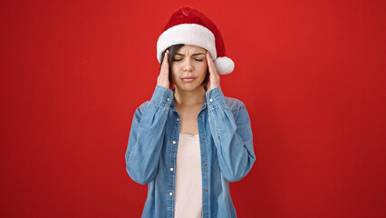 Young caucasian woman wearing christmas hat having headache over isolated red background