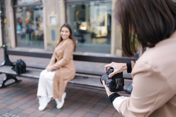 First person view of photographer making photo while beautiful woman sitting on bench