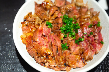 Japanese bowl of rice topped with beef steak medium rare served in restaurant.