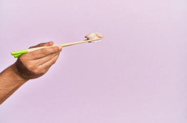  Hand of man holding scallop nigiri with chopsticks over isolated pink background
