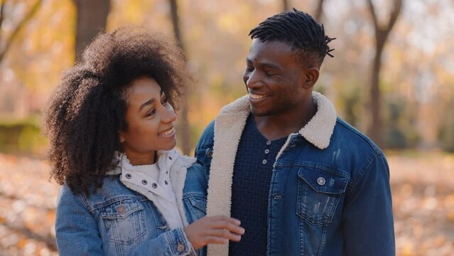 Smiling black couple stands surrounded by autumn beauty hugging