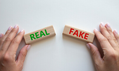 Real or Fake symbol. Concept word Real or Fake on wooden blocks. Businessman hand. Beautiful white background. Business and Real or Fake concept. Copy space