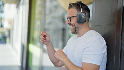 Grey-haired man listening to music and dancing at street