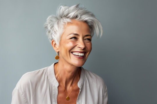 Portrait of a happy senior woman smiling on grey background. Copy space