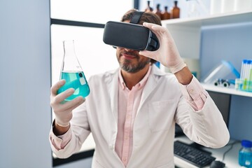 Middle age man scientist using virtual reality glasses holding test tube at laboratory