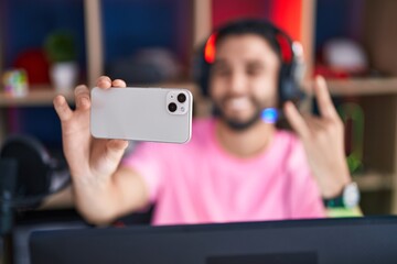 Young arab man streamer smiling confident make selfie by smartphone at gaming room