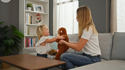 Happy caucasian mother and little daughter comfortably enjoying and playing with toys at home,...