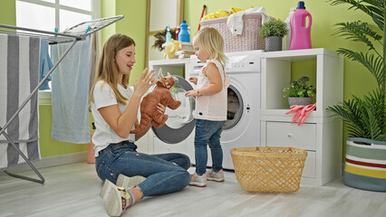 Happy caucasian mother & daughter washing toys infusing joy into laundry room chores