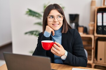 Young beautiful hispanic woman business worker using laptop drinking coffee at office