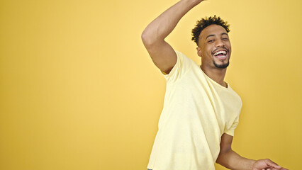 African american man smiling confident dancing over isolated yellow background