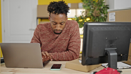 African american man ecommerce business worker using laptop and smartphone at office