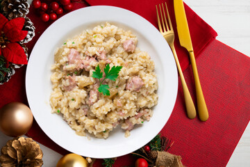Catalan butifarra sausage risotto with parmesan. Mixed Spanish and Italian recipe.. Christmas food served on a table decorated with Christmas motifs.