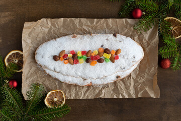 Delicious Christmas stollen with nuts, candied fruits and spices on a brown wooden background. Traditional Christmas pastries. Close-up, top view