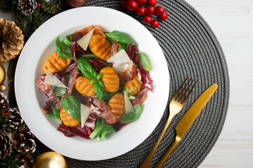 Gnocchi salad with bacon and Italian cheese. Christmas food served on a table decorated with Christmas motifs.