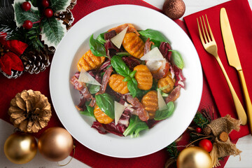 Gnocchi salad with bacon and Italian cheese. Christmas food served on a table decorated with Christmas motifs.